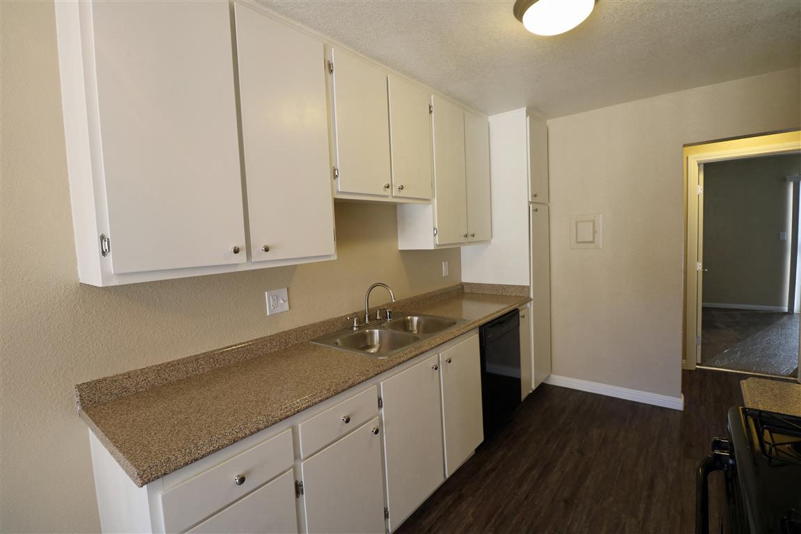 A kitchen with white cabinets and a granite countertop.